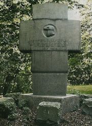 Die Rückseite des Gedenkkreuzes an der Waldkirche mit Adlerkopf und bewegendem Spruch.